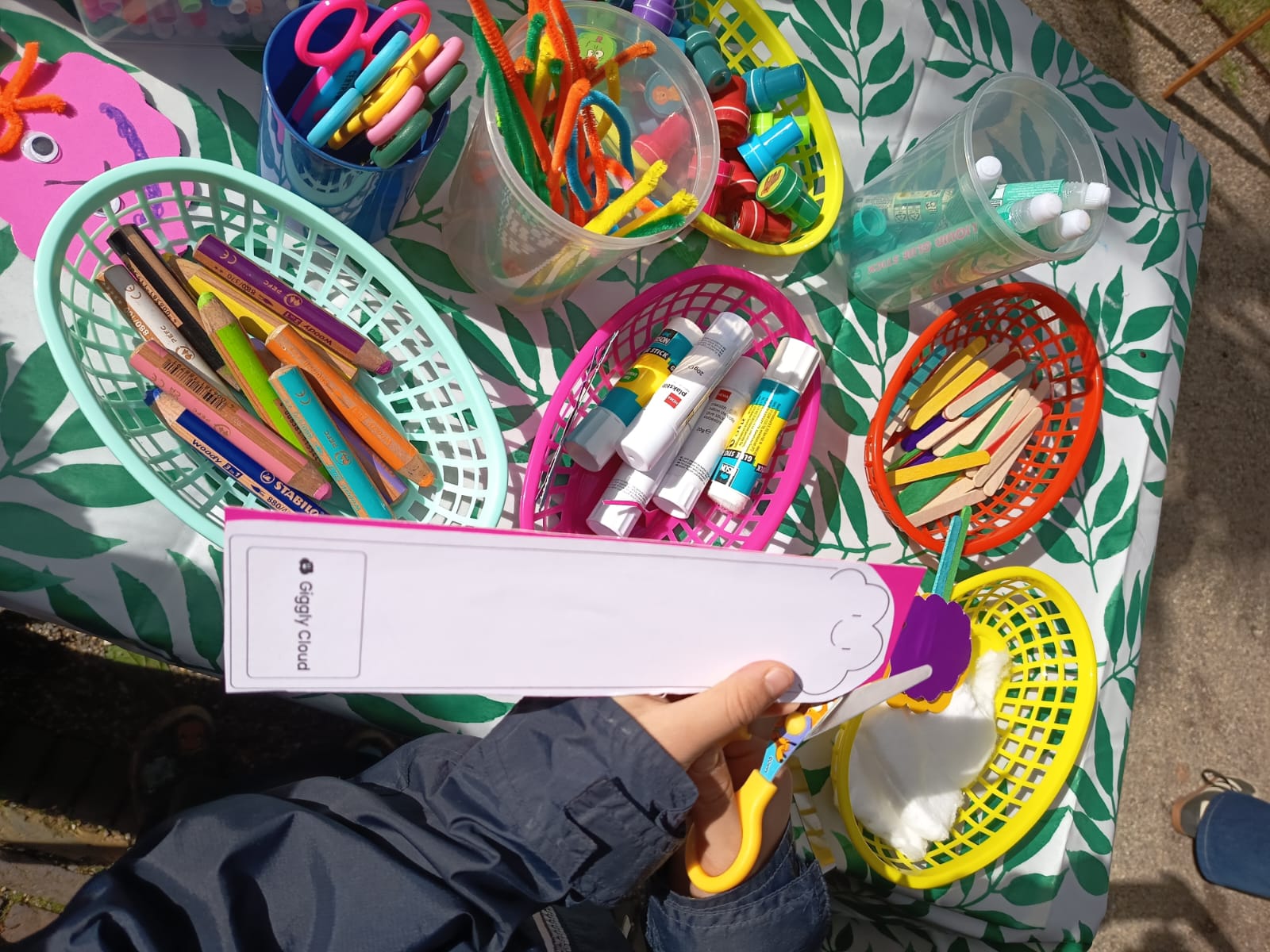A child decorating a Giggly Cloud bookmark with stickers and colouring pens.