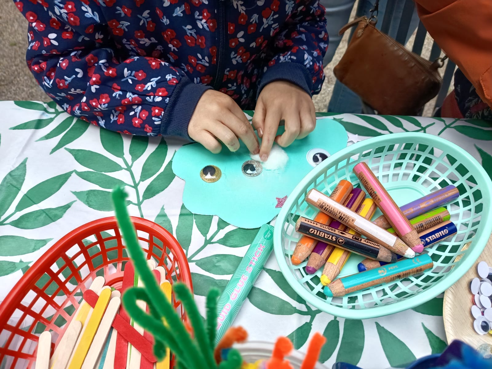 Little hands gluing cotton onto a cloud craft at the book swap.