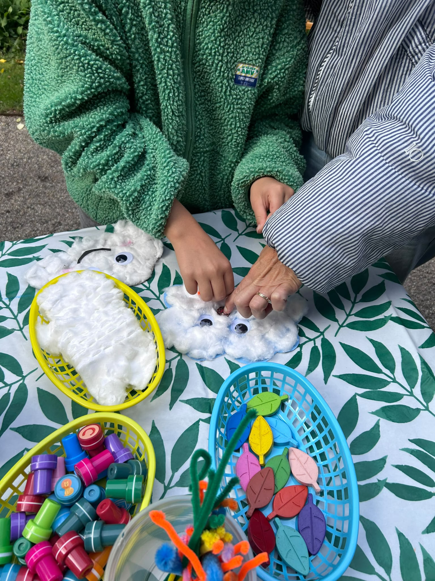 Child and grown-up making cotton cloud crafts together at the book swap.