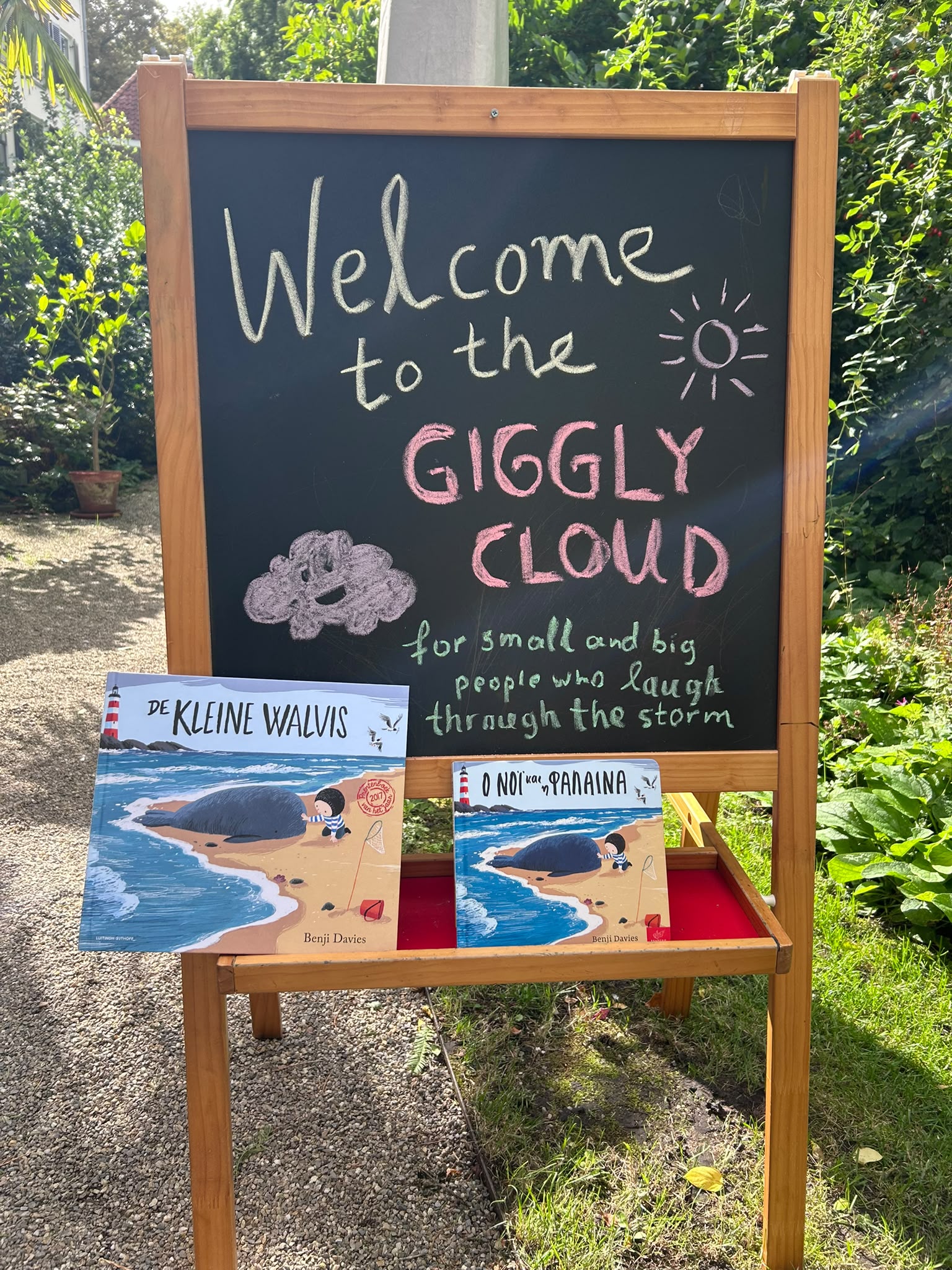 Chalkboard welcome sign for Giggly Cloud with children's books at a book swap.
